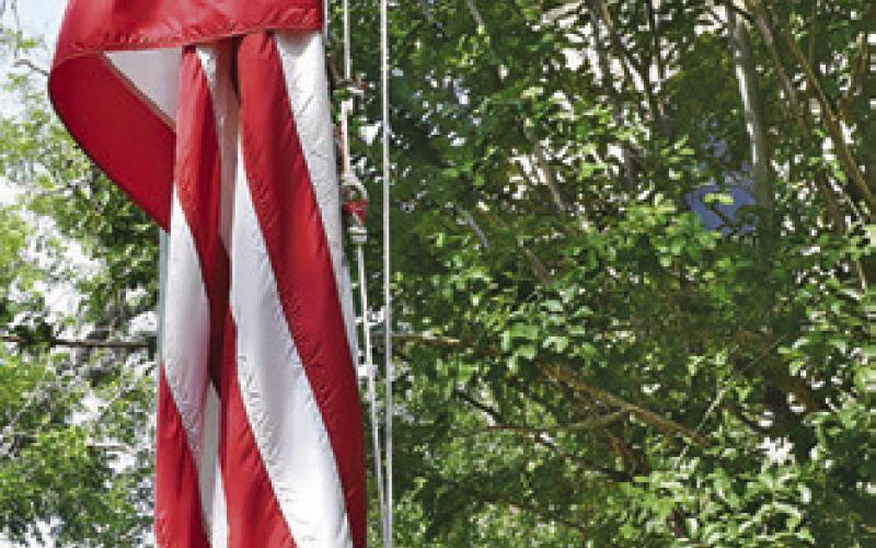 CALEB KENNEY raises the flags on Monday during the Memorial Day ceremony at the Burleson County War Memorial.