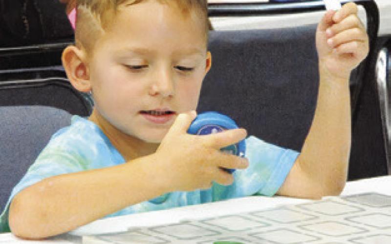 CHILDREN WERE fascinated by the tiny, programmable robots which “sparked” their curiosity at the Harrie P. Woodson Memorial Library “Spark” event last Thursday. Tribune photo by Denise Squier