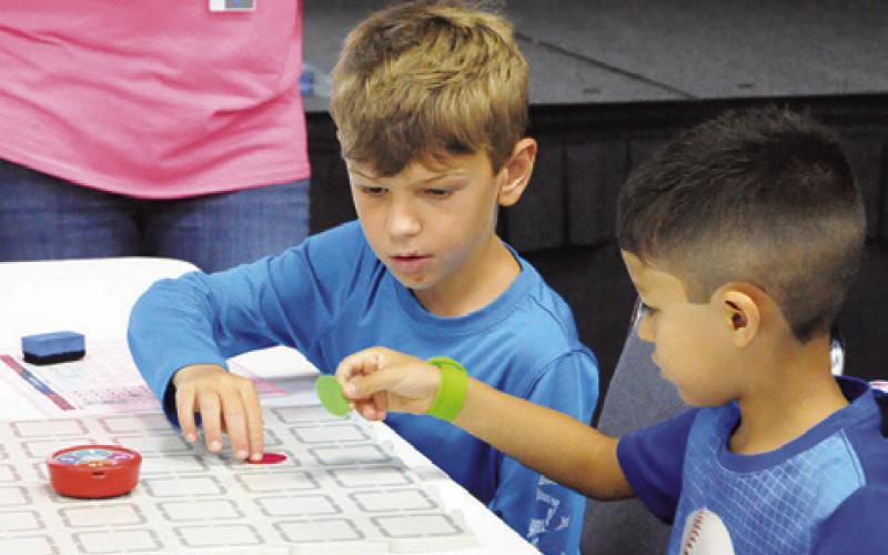 CHILDREN PROGRAMMED disc-shaped robots to travel to points in a grid during the Harrie P. Woodson Memorial Library “Spark” event last Thursday at the Caldwell Civic Center. Tribune photo by Denise Squier