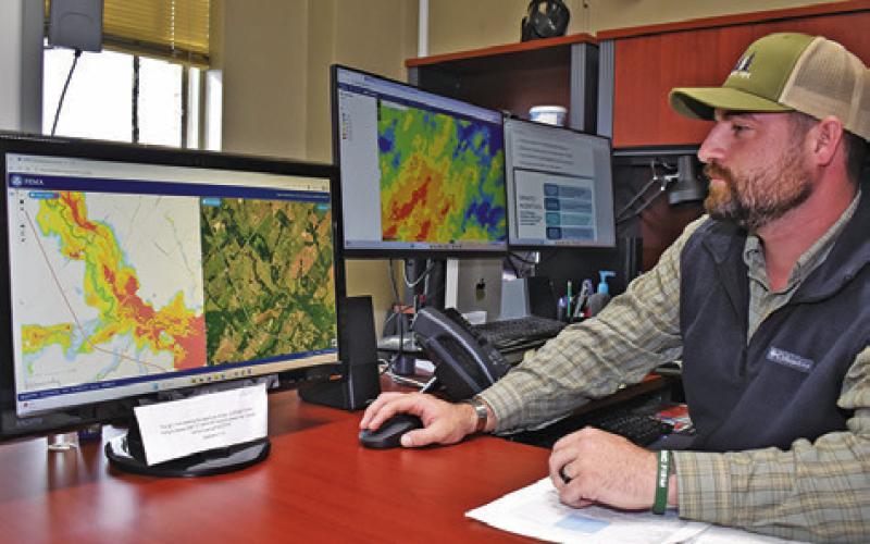 BURLESON COUNTY EMERGENCY Management Coordinator Ty Eller looks at these area maps in his office at the courthouse. Tribune photo by Roy Sanders
