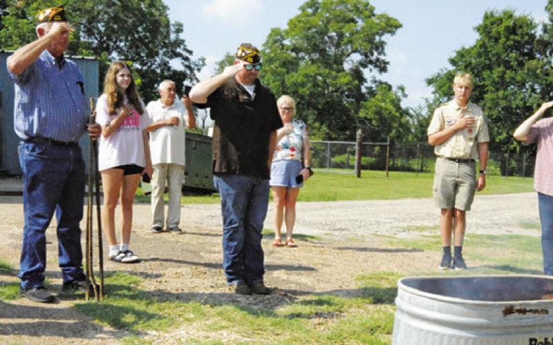 MEMBERS OF VFW POST 4458 and county residents salute burning flags which were retired during a flag retirement ceremony last Friday, Flag Day. -- Tribune photo by Denise Squier