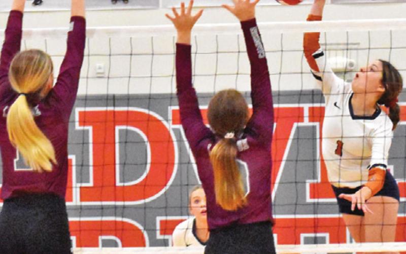 CALDWELL’S ASHLYN KELLUM hits the ball over two blockers last Friday during the Lady Hornets’ district loss to Cameron Yoe.
