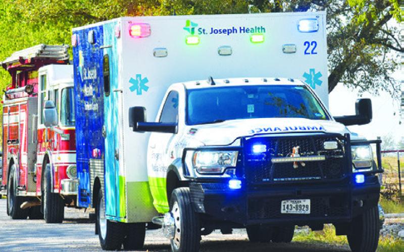 AN AMBULANCE CREW and firefighters respond on County Road 116.