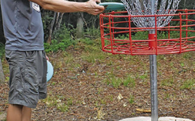 DUSTIN SANFORD works on Monday at Caldwell’s expanded disc golf course.