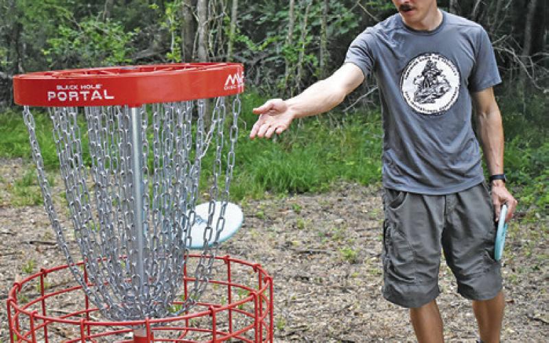 DUSTIN SANFORD IS at the new, expanded disc golf course on Monday at John E. Hejl Park. -- Tribune photo by Roy Sanders