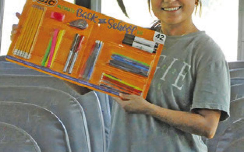 MACY NARRO shows off this set of pens, pencils and markers during the “Stuff the Bus,” sponsored by Burleson County Cops 4Kids and the Texas A&amp;amp;M AgriLife Extension Office. Tribune photo by Denise Squier