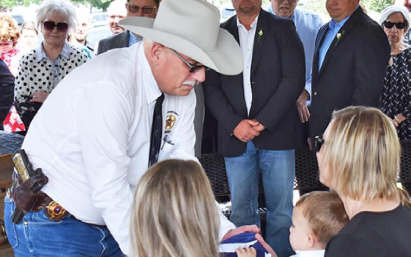 BURLESON COUNTY SHERIFF Gene Hermes presents this flag to Cindy See and the See family at the Tuesday burial at Caldwell Masonic Cemetery. See was a longtime Burleson County law officer, known for his devotion to duty and a wry sense of humor.