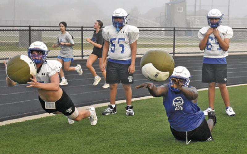 SNOOK PLAYERS TOSS these medicine balls during practice. Tribune photo by Roy Sanders
