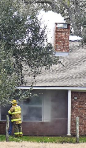 FIREFIGHTERS EXTINGUISH this blaze on Feb. 19 at a house off F.M. 975 near Caldwell. Tribune photo by Roy Sanders