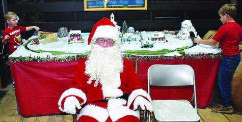 SANTA CLAUS GREETS visitors as children play behind him on Saturday at the Deanville Heritage Foundation’s Hot Cocoa, Cookies &amp; Santa celebration at the Deanville Depot.