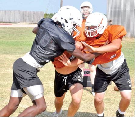 CALDWELL’S BRANDON WILLIAMS, left, and Tristan Ballard and Collin Gammage practice on Monday to get ready for the Friday opener against Edna. -- Tribune photo by Roy Sanders