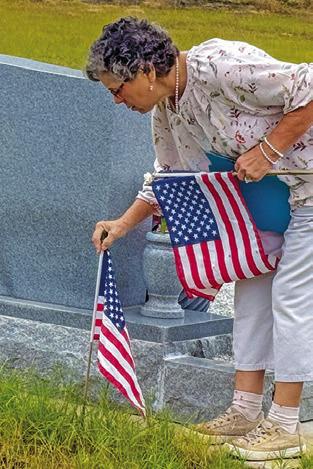 DANA YEZAK PLACES a flag at a grave marker in the Snook Cemetery on Saturday in observance of Veterans Day. Tribune photo by Denise Squier