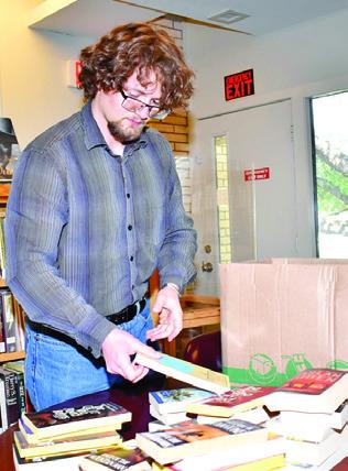 ASH BOSTIC looks over these books at the Harrie P. Woodson Memorial Library.