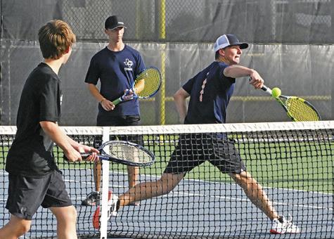 CALDWELL’S BRYCE BARR hits the ball while his doubles partner Blane Barr watches during their match against a Giddings duo. Tribune photo by Denise Squier