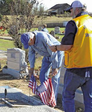 SNOOK LI ONS CLUB members Steve Tunnell and John Pollock place flags at a veteran’s grave in the Snook Cemetery on Saturday. Tribune photo by Denise Squier