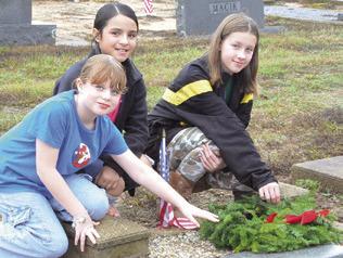 THESE GIRLS placed a wreath on a veteran’s grave in the Snook Cemetery as part of the Wreaths Across America campaign. The event was headed by the Snook Extension Education Association (EEA). Tribune photo by Denise Squier