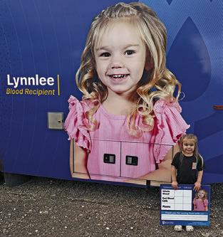 LYNNLEE KOCUREK stands next to this picture of herself on the blood donor van last Sunday at the Deanville Volunteer Fire Department. A replenishment blood drive was held.