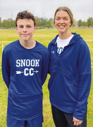 ETHAN JANAC is joined by his coach Meagan Mitchell at the state cross country meet.