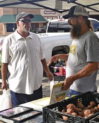 ERIC BONIOL, right, works on Saturday at the Farmers Market in downtown Caldwell.