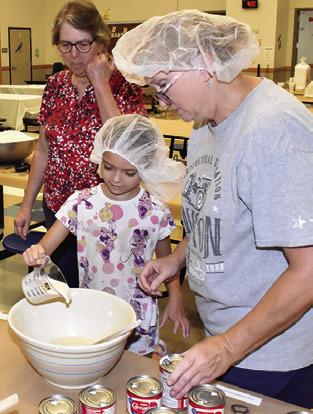 LAURA SEBESTA helps Kinsley Crump mix the dough for the kolaches at this kolache baking lesson on Saturday at Snook Elementary School. Sharon Kovar, left, observes.
