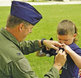 COLONEL LANCE Burnet, USAF (ret.), places wings on this child during last Thursday’s Harrie P. Woodson Library’s “Ready for Take-Off!” event featuring planes.
