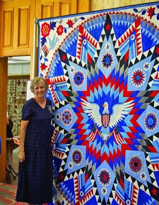 LOCAL QUILTER MARY WOLZ is pictured with her patriotic quilt at the Creative Memories Quilt Guild Quilt Show. Tribune photo by Sabine Lazo
