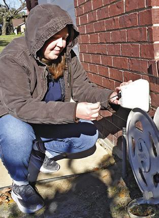 KIMBERLY HUTCHESON checks the covering of this outdoor water spigot as the recent Arctic blast arrived in Burleson County. Tribune photo by Roy Sanders