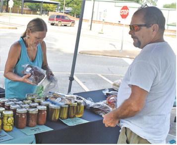VICKIE DASH VISITS with a customer on Saturday at the weekly farmers market in downtown Caldwell. Local residents enjoy the market.