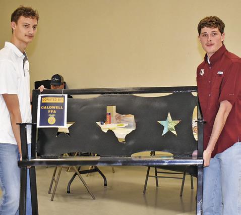 COOPER ODENBACH AND Nathan Scott display this auction item on Saturday at the Burleson County Go Texan Annual Auction.