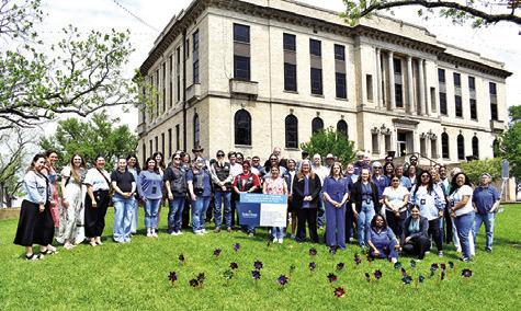 ATTENDEES OF THE CHILD Abuse Awareness and Prevention Month ceremony are pictured with the 39 pinwheels, planted to symbolize victims of child abuse in Burleson County. Tribune photo by Roy Sanders