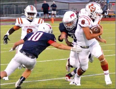 LOGAN KNESEK OF Caldwell carries the ball against Madisonville. Also pictured is Nicolas Johnson. Caldwell won 12-6 for its first win of the season. -- Tribune photo by Roy Sanders