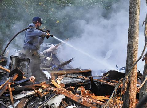 A FIREFIGHTER WASHES down the debris at this fire on Friday, Aug. 15, on North Gray Street. See story page 3A.