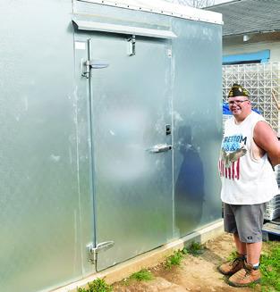 DAVID PALICKA STANDS next to the cooler made possible from grant funding. -- Tribune photo by Roy Sanders