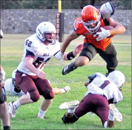 SOMERVILLE’S JEREMIAH TEAGUE leaps over these Iola defenders last Friday in the Yeguas 20-12 home loss. Somerville faces Texas Wind this week. -- Tribune photo by Roy Sanders