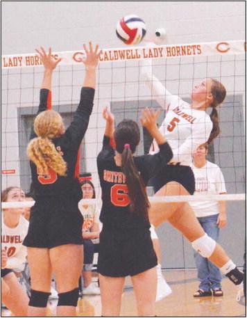 CALDWELL’S KYSEN TONEY hits the ball over two Smithville blockers during the Lady Hornet’s district win last Friday night.