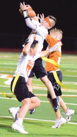 KRUSH STRANGE leaps to intercept the ball during the Alliance Youth Football League’s Division D3 Super Bowl last Thursday at Hornet Stadium. Also pictured are Caden Qualls, white jersey, and Hudson Novosad, orange jersey. -- Tribune photo by Denise Hornaday