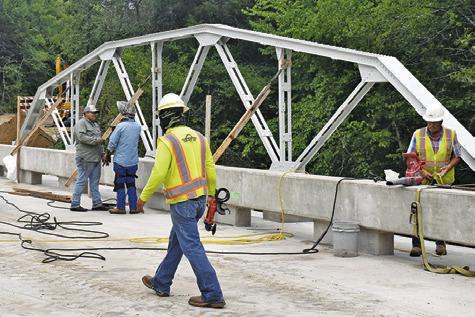 BRIDGE WORK CONTINUES on County Road 146 on Thursday, July 3. The old trusses were preserved and added onto the bridge. Tribune photo by Roy Sanders