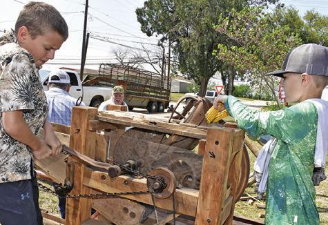 RHETT HARTMAN AND Brooks Urbanosky try out this corn grinder at a demonstration on Saturday, March 28, at the Burleson County Czech Heritage Museum’s annual Heritage Day.