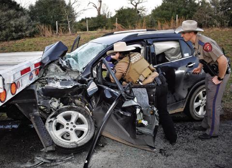 LAW OFFICERS WORK AT this fatal accident on Saturday on State Highway 21 West. Tribune photo by Roy Sanders