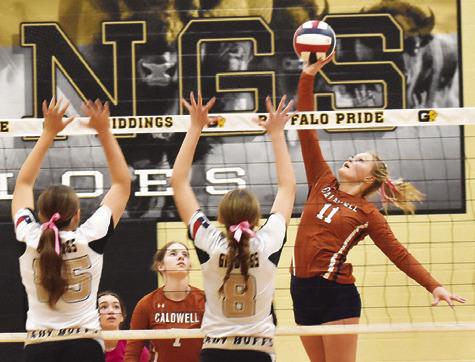 CALDWELL’S REESE MCMANUS hits the ball over Giddings’ blockers, Caedon Melcher and Aliza Rodriguez, during the Caldwell-Giddings district match last Friday night. Tribune photo by Roy Sanders