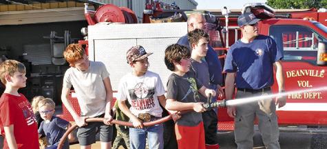 FUTURE FIREFIGHTERS SPRAY water under the supervision of Nathan Flippin and Jeff Baldwin on Saturday at the Deanville Volunteer Fire Department’s Community Night Out.