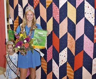 BURLESON COUNTY FAIR Queen Hadleigh Novosad displays her grand champion quilt from the Burleson County Fair and is joined by Little Miss Avery Grace Freeman.