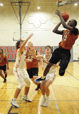 SHAGARIUS HARRISON LEAPS high for this shot as varsity’s Koy Macik and Caden Zboril defend. Also pictured for the alumni are Deautre Burns and Chase Stewart. Tribune photo by Denise Squier