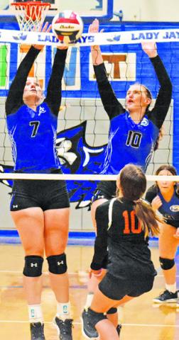 ALEXIS MACIK and Payton Sodolak reach to block a hit during Friday’s Lady Jay win over Buckholts 25-20, 25-19, 25-9.