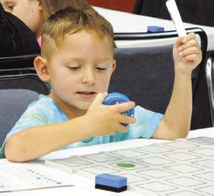 CHILDREN WERE fascinated by the tiny, programmable robots which “sparked” their curiosity at the Harrie P. Woodson Memorial Library “Spark” event last Thursday. Tribune photo by Denise Squier
