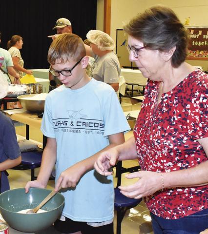 SHARON KOVAR helps Shane Keinow mix the kolache dough.