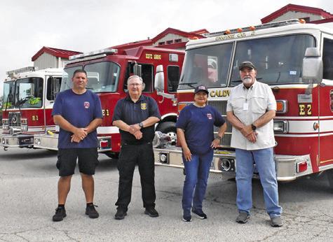 CALDWELL VOLUNTEER FIREFIGHTERS, from left, Mark Foisie, Harry Bowers, Polly Bowers and retired firefighter Doug Beavers stand next to these fire trucks at the fire station.