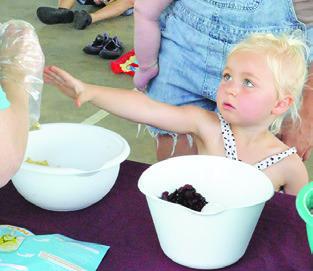 CHILDREN ATTENDING last Thursday’s special library event at Davidson Creek Park were taught what to include in trail mix. This child is ready to enjoy her specialized mix.