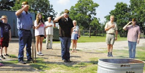 MEMBERS OF VFW POST 4458 and county residents salute burning flags which were retired during a flag retirement ceremony last Friday, Flag Day. -- Tribune photo by Denise Squier