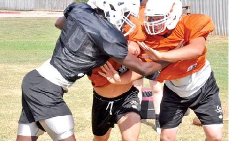 CALDWELL’S BRANDON WILLIAMS, left, and Tristan Ballard and Collin Gammage practice on Monday to get ready for the Friday opener against Edna. -- Tribune photo by Roy Sanders